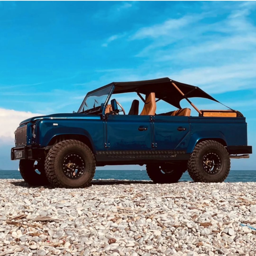 Land Rover Defender restauré bleu marine au bord de l'eau