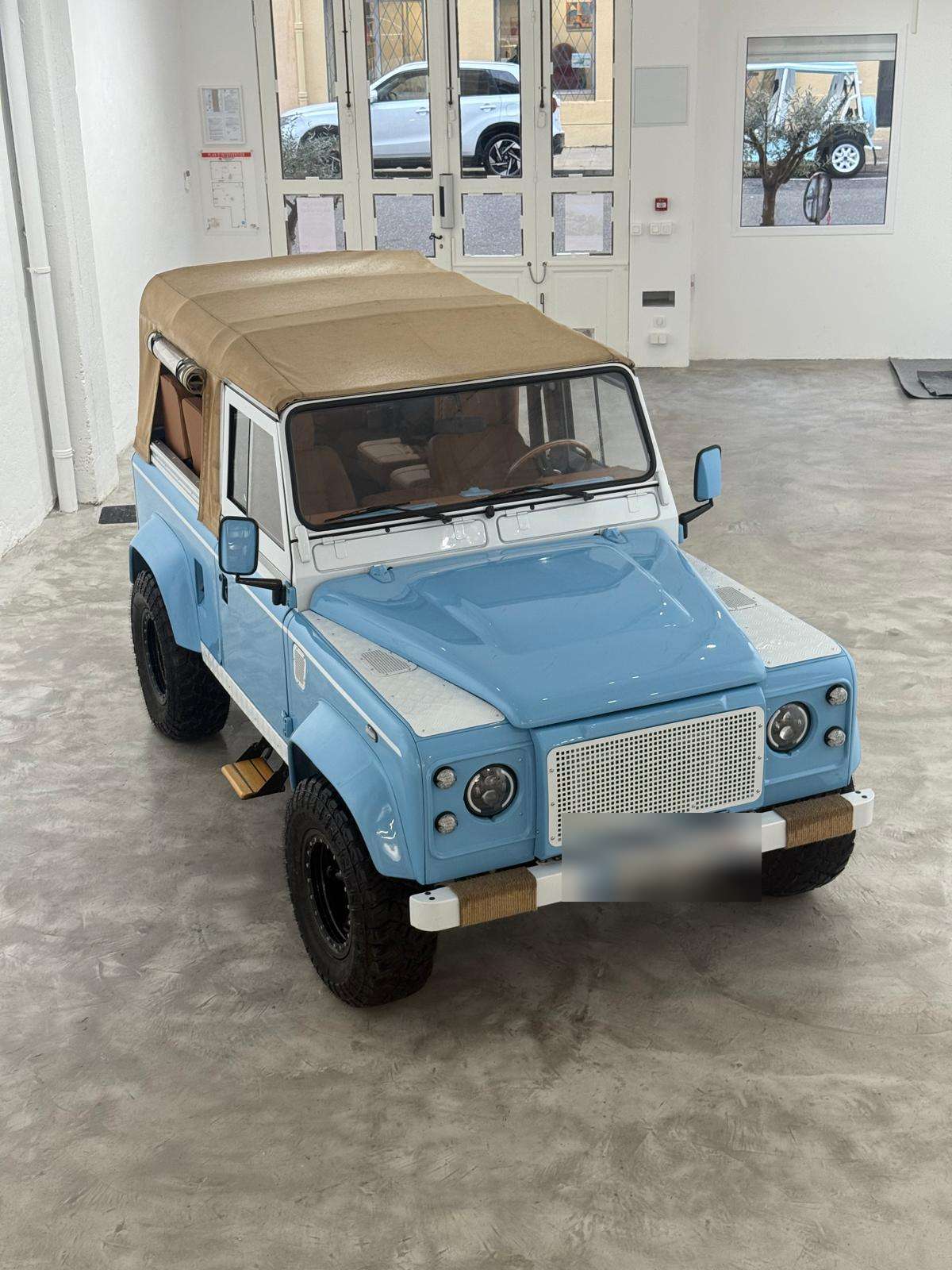 Defender bleu clair à capote beige dans le showroom