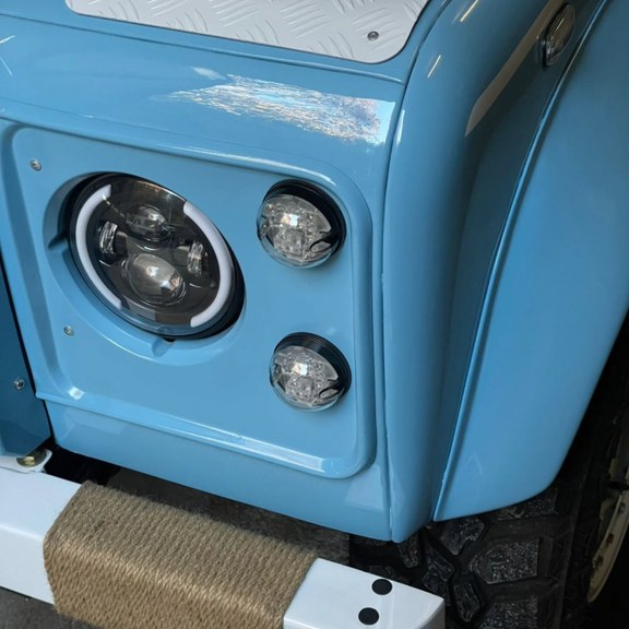 Détail Classic Defender — optique LED et feux ronds sur carrosserie bleu ciel
