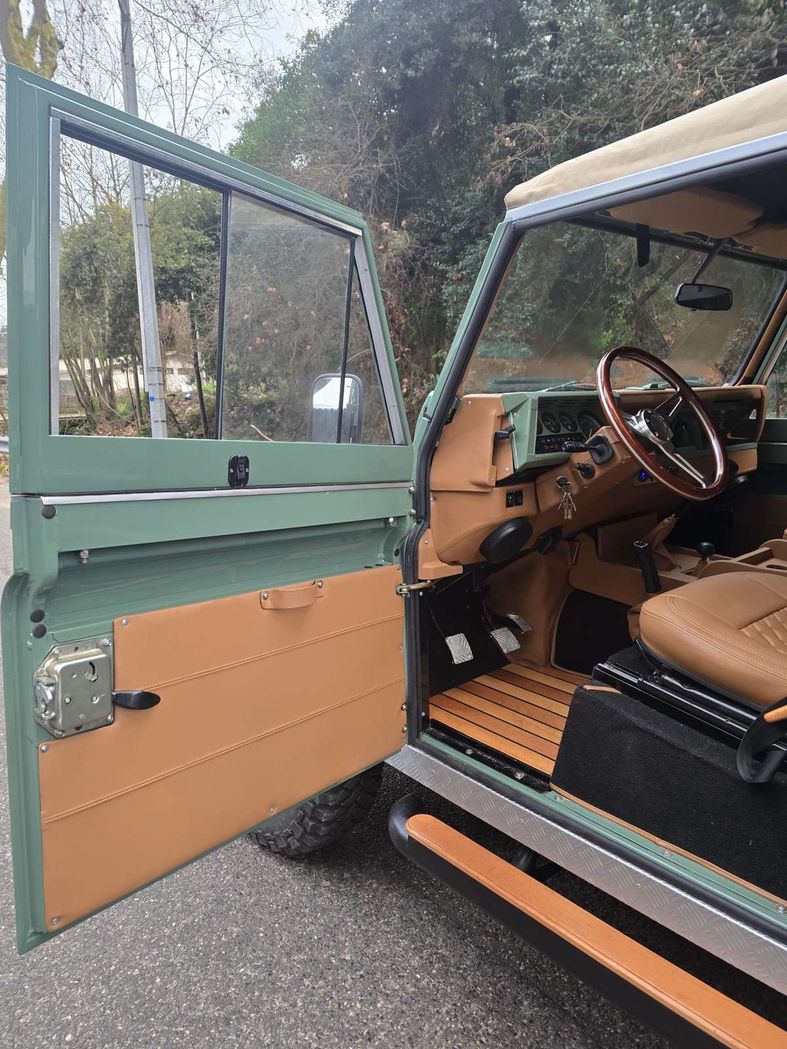 Porte ouverte sur l'habitacle d'un Defender vert restauré