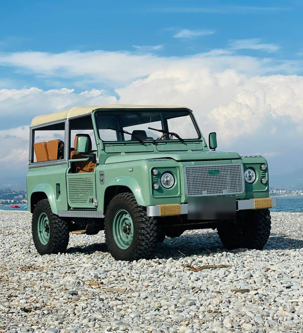 Defender vert clair restauré sur une plage de galets